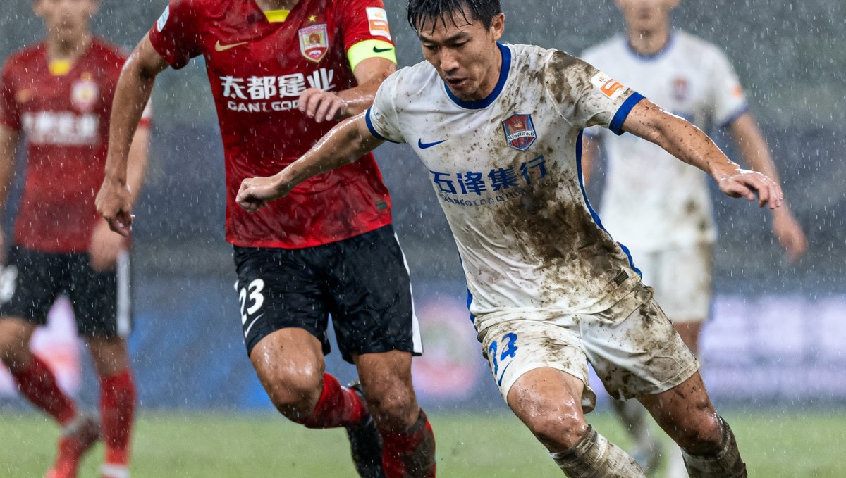 中超联赛冠军争夺战关键比赛现场，双方球员在雨中奋力拼抢，球衣上沾满泥水，展现出不屈的竞技精神